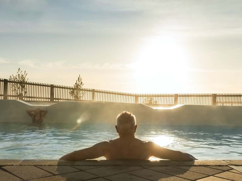 Man looking towards the sun while soaking in a hot pool