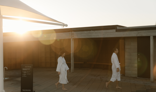 Two people wearing robes walking through the He Puna Taimoana facility