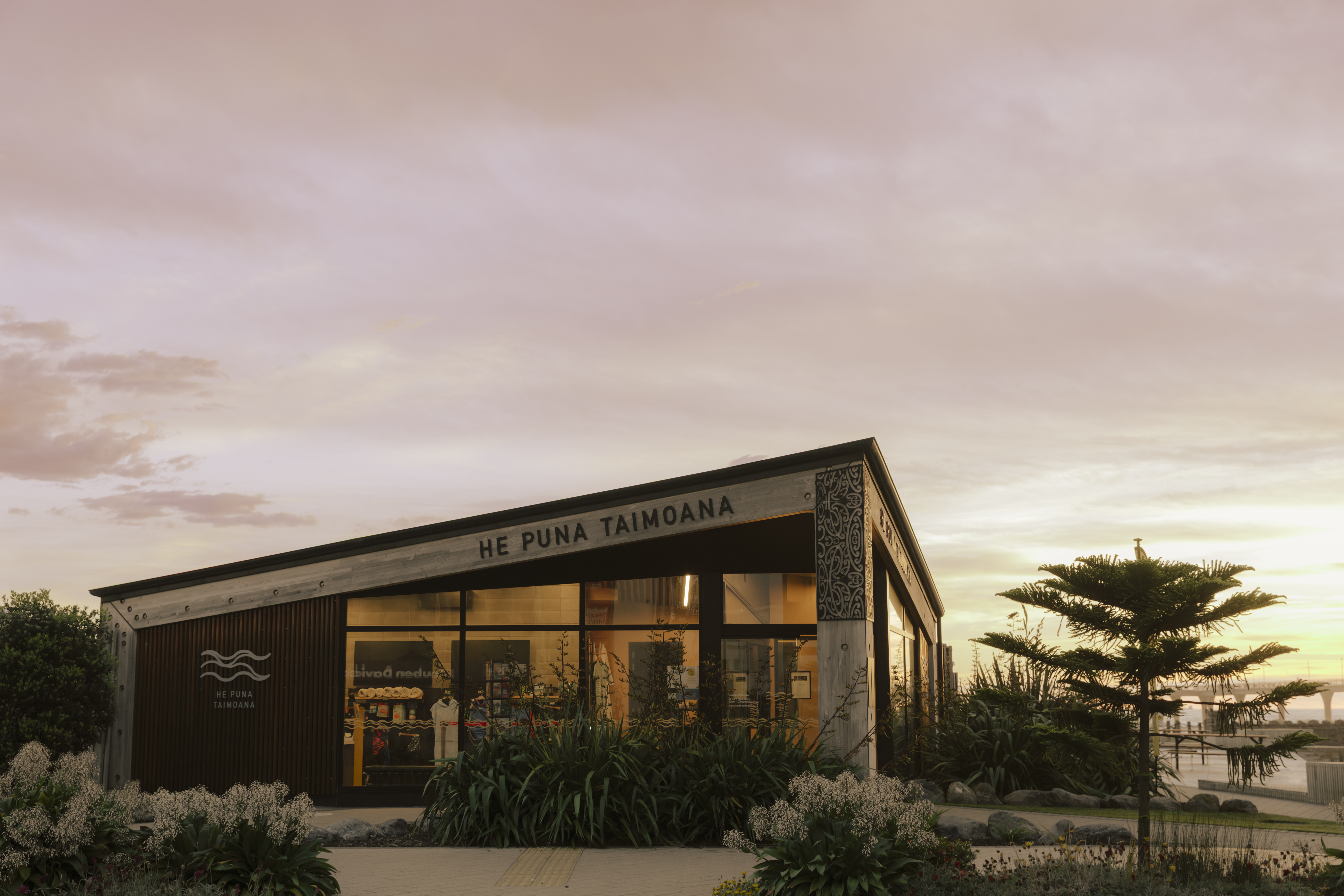 Exterior of the He Puna Taimoana building, showcasing the modern coastal design and entrance to the beachfront hot pools facility